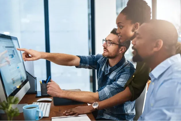 Three professionals reviewing information on a desktop screen